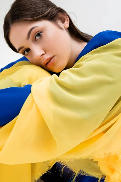 Tender ukrainian young woman in blue and yellow outfit looking at camera isolated on grey — Stock Photo