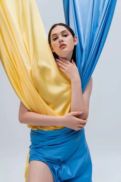 Morena joven ucraniana en vestido azul y amarillo aislado en gris - foto de stock