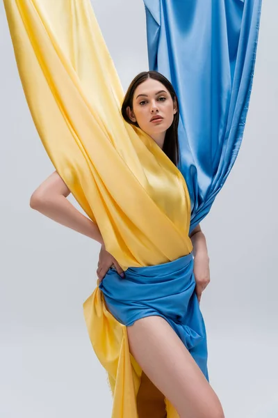 Patriotic and young ukrainian woman in blue and yellow dress posing isolated on grey — Photo de stock