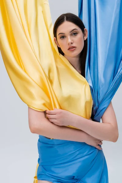 Sinnliche junge Ukrainerin in blau-gelbem Kleid posiert isoliert auf grau — Stockfoto