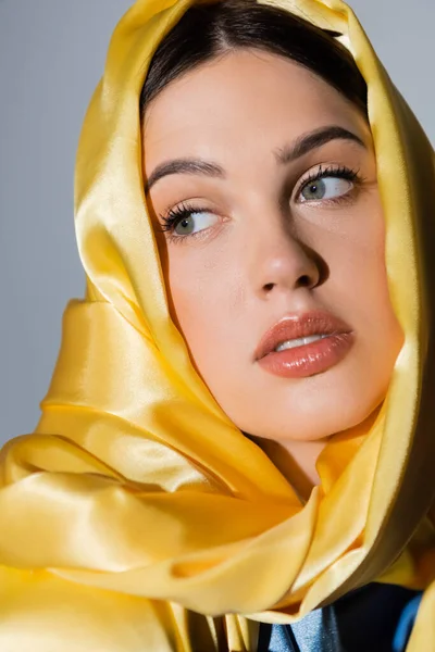 Jeune femme ukrainienne en foulard de soie jaune regardant loin isolé sur gris — Photo de stock