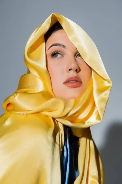 Jolie femme ukrainienne en foulard de soie jaune regardant loin isolé sur gris — Photo de stock