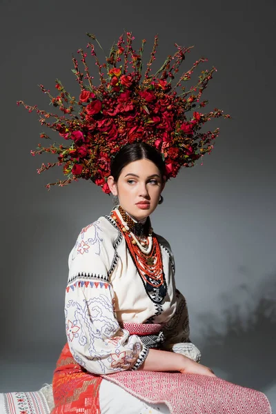 Portrait of young ukrainian woman in traditional clothing and floral wreath on grey — Foto stock