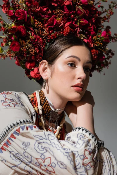 Portrait of dreamy ukrainian woman in traditional clothes and floral red wreath isolated on grey — Fotografia de Stock