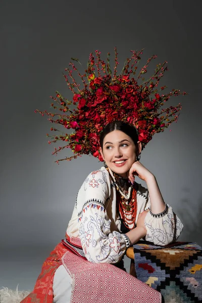 Happy ukrainian woman in traditional clothes and floral red wreath on grey — Stock Photo