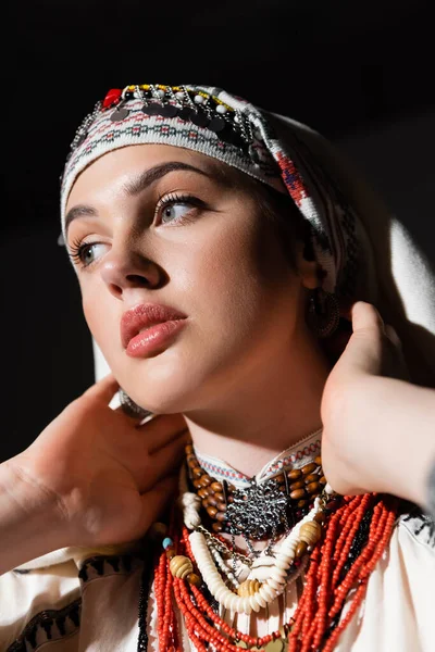 Portrait of ukrainian woman in headwear with ornament posing isolated on black — Stock Photo