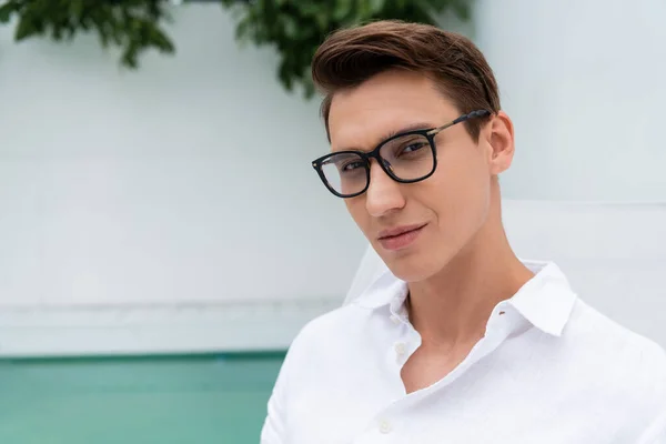 Man in white shirt and eyeglasses looking at camera at poolside outdoors — Stockfoto