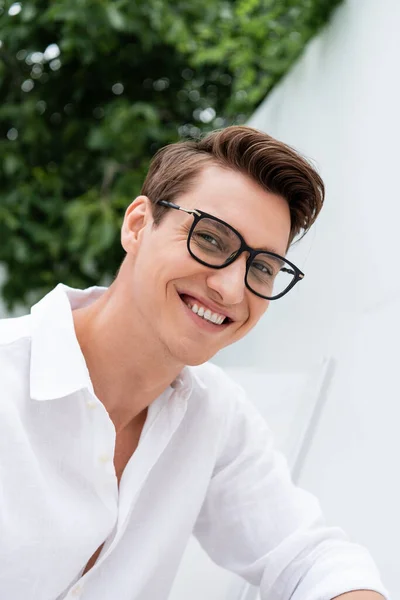 Glücklicher Mann in weißem Hemd und Brille, der draußen in die Kamera schaut — Stockfoto