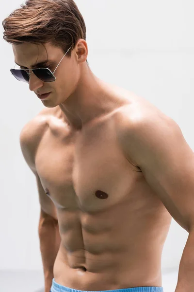 Shirtless man with muscular torso wearing sunglasses on white background - foto de stock