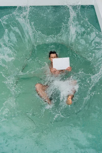 Vista superior do freelancer com laptop caindo na piscina com água azul-turquesa — Fotografia de Stock