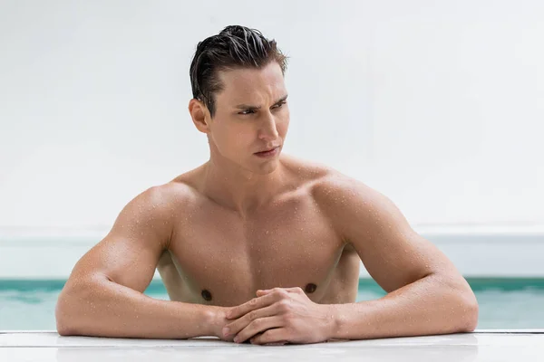 Bagnato e pensoso uomo con il corpo muscolare guardando lontano a bordo piscina — Foto stock