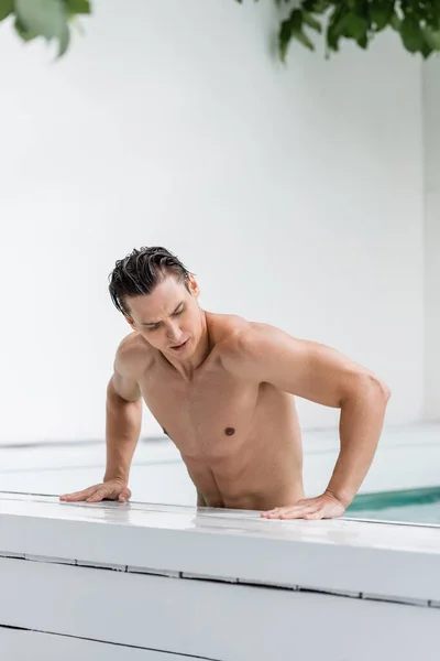 Athletic man with wet hair getting out outdoor pool — Stock Photo
