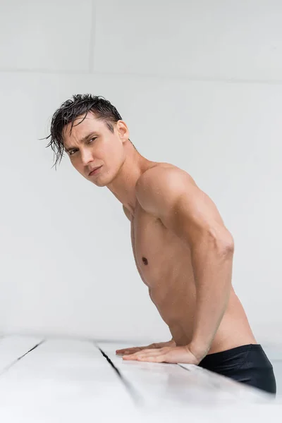 Athletic man with wet body and hair looking away at poolside — Stock Photo