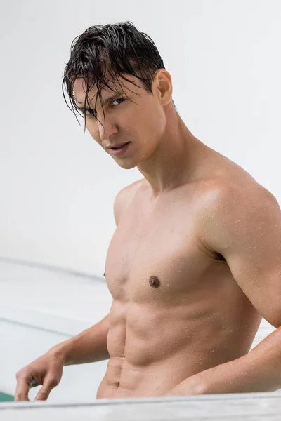 Athletischer Mann mit nassem Körper und nassen Haaren blickt in die Kamera — Stockfoto