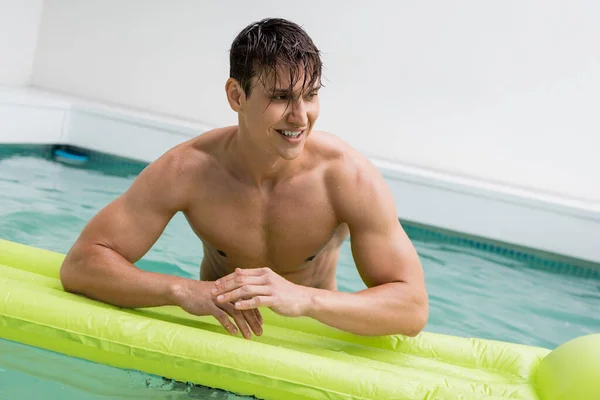 Allegro e bagnato uomo guardando lontano vicino materasso nuoto in piscina — Foto stock