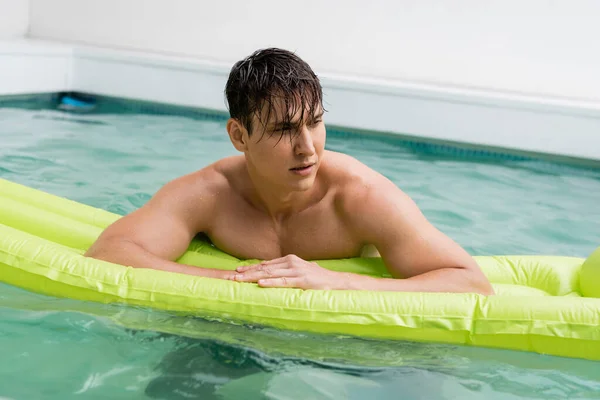 Sportive man with wet hair on swimming mattress in outdoor pool — Stock Photo