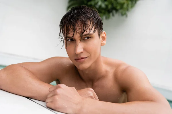 Мужчина со спортивным телом и мокрыми волосами, смотрящий в сторону бассейна — стоковое фото
