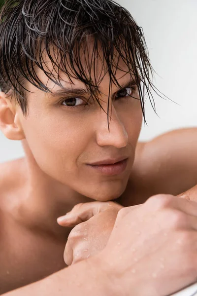 Close up retrato do homem molhado com a pele perfeita olhando para a câmera isolada no branco — Fotografia de Stock