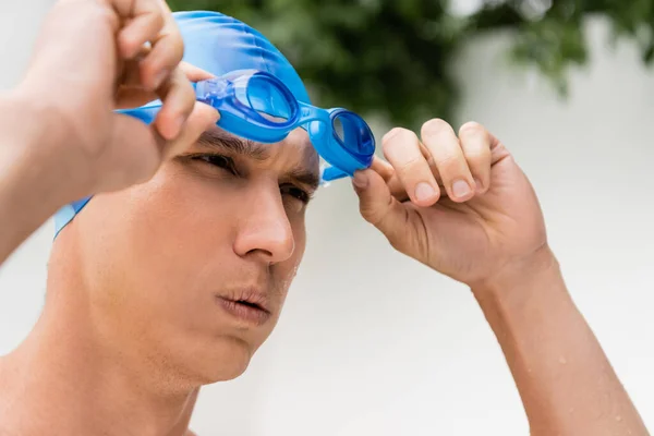 Portrait of focused sportsman in swimming cap wearing goggles — стоковое фото
