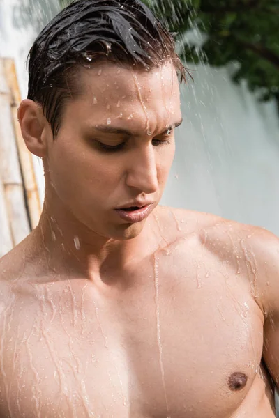 Man with athletic body taking shower outdoors — стоковое фото