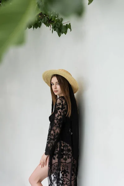 Stylish woman in guipure robe and sun hat looking at camera at resort — Stockfoto