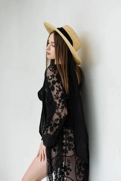 Young woman in swimsuit and robe standing near wall at resort - foto de stock