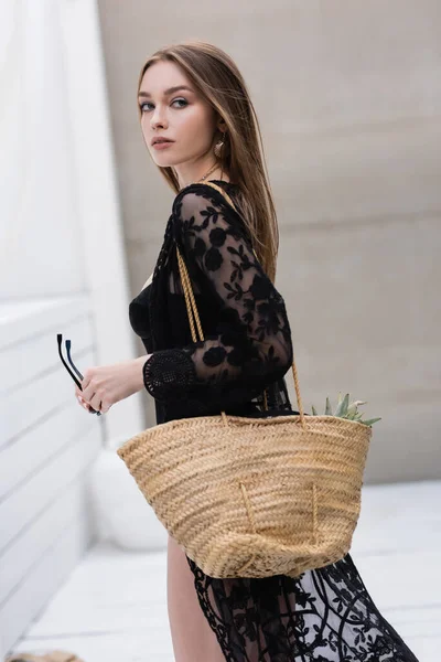 Trendy woman with handbag and sunglasses standing at resort — Foto stock