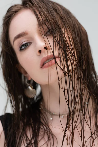 Portrait of young woman with makeup and wet hair looking at camera outdoors — Stock Photo