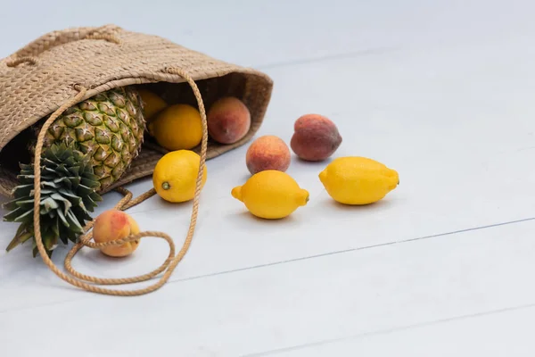 Fresh tropical fruits in straw handbag on floor at resort — стоковое фото