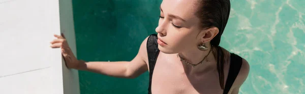 Вид зверху на молоду жінку в стильному купальнику, що плаває в басейні, банер — стокове фото