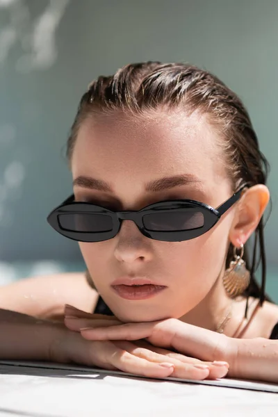 Porträt einer hübschen jungen Frau mit nassen Haaren und stylischer Sonnenbrille beim Sonnenbad draußen — Stockfoto