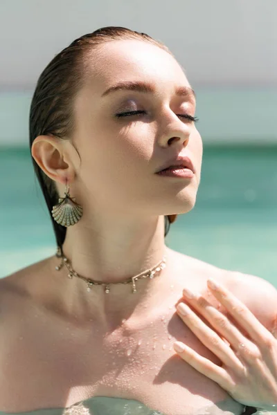 Portrait of pretty woman in accessories and wet hair sunbathing near swimming pool — Foto stock