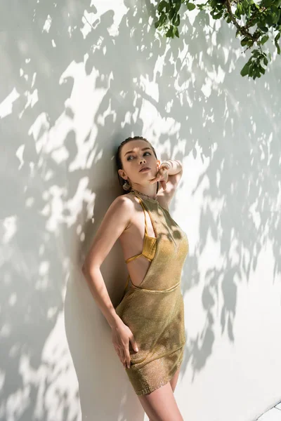 Hübsche Frau im Sommerkleid steht in der Nähe einer Wand mit Schatten — Stockfoto