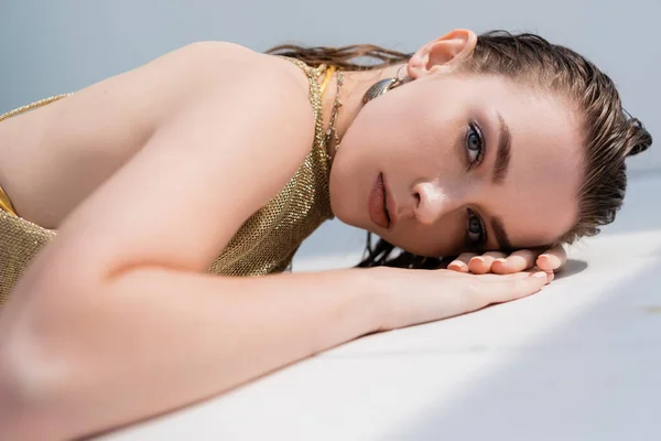 Young woman in summer dress lying on white surface and looking at camera — Foto stock