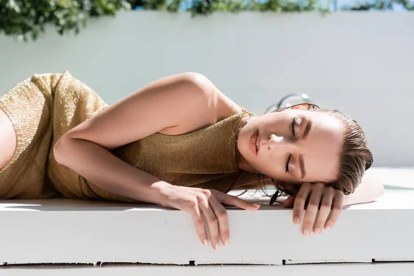 Hübsche junge Frau mit geschlossenen Augen posiert im Sommerkleid am Pool — Stockfoto