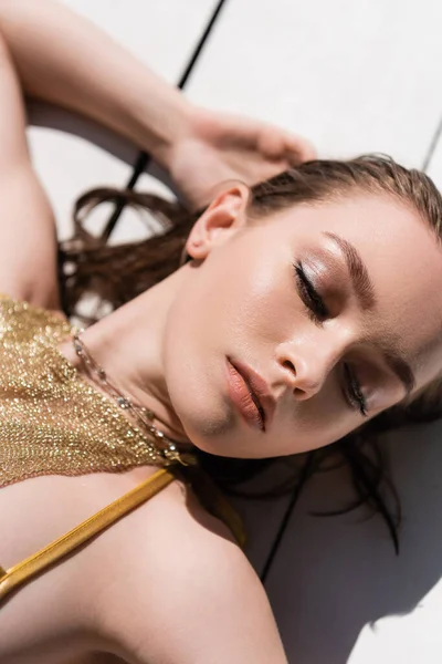 Top view of pretty woman with makeup lying on white wooden surface — Fotografia de Stock