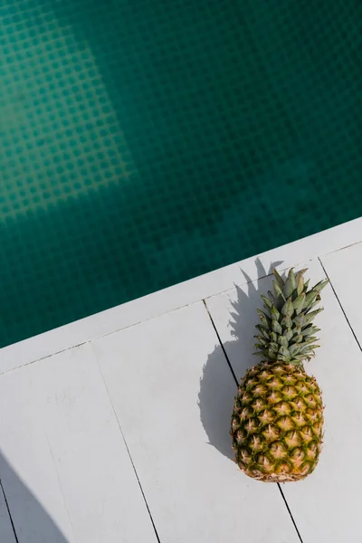 Blick von oben auf tropische und süße Ananas in der Nähe von blauem Wasser im Schwimmbad — Stockfoto
