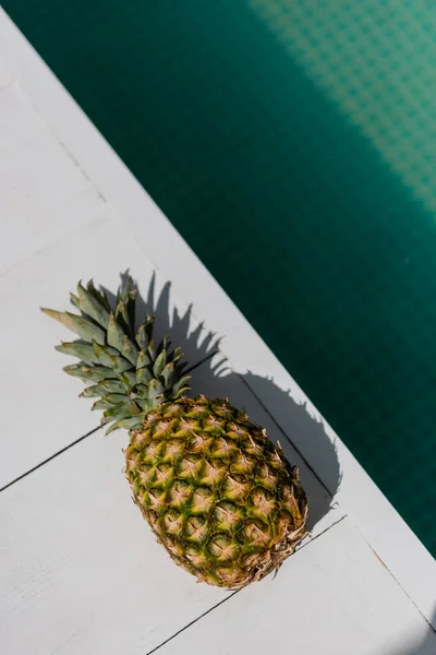 Вид зверху на тропічний і стиглий ананас біля блакитної води в басейні — стокове фото