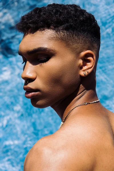 Portrait african american man with piercing and necklace near blue drapery on background — Photo de stock