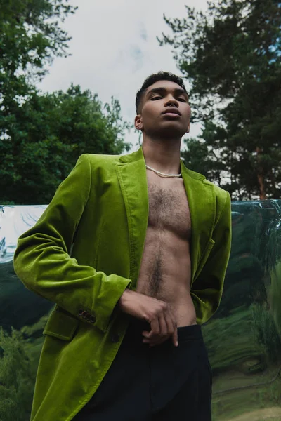 Low angle view of african american man in green velvet blazer near flexible mirror in park — Fotografia de Stock