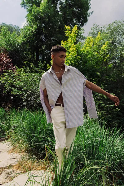 Young african american man in stylish shirt posing in park on summer day — Photo de stock