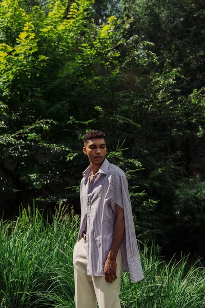 Young african american man in fashionable shirt posing in summer park — Stock Photo