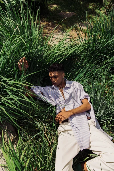 High angle view of trendy african american man sleeping on grass in park — Stockfoto