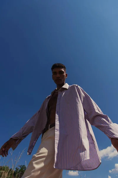 Low angle view of stylish african american man in blue shirt under clear sky — Stock Photo