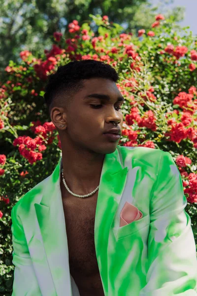 Trendy african american man in piercing and beads posing in park — Stockfoto