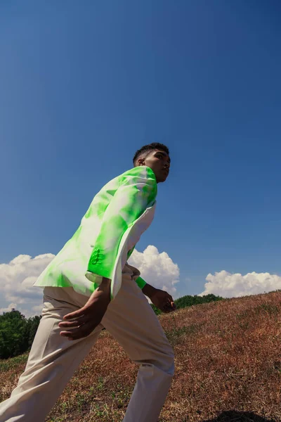 Афроамериканець у стильному білому і зеленому бліцері, який ходить у полі. — стокове фото