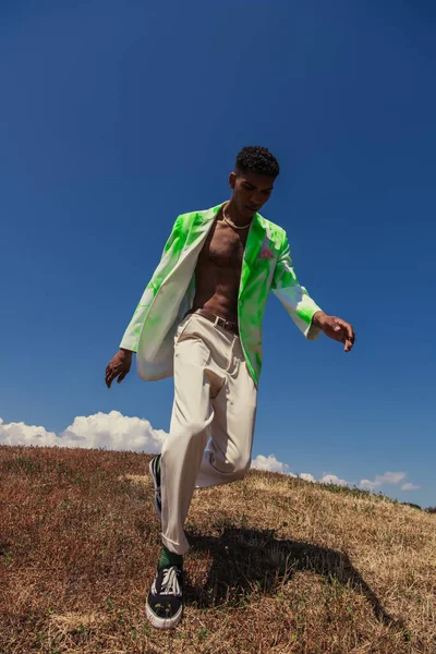 Повна довжина модного афроамериканця, що біжить в полі в літній день — стокове фото