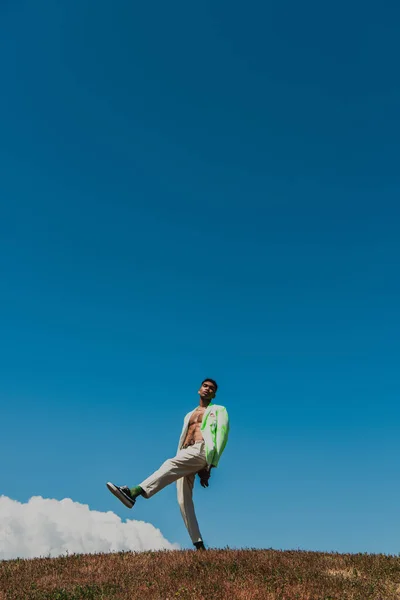 Young and trendy african american man posing in meadow under clear sky — Fotografia de Stock