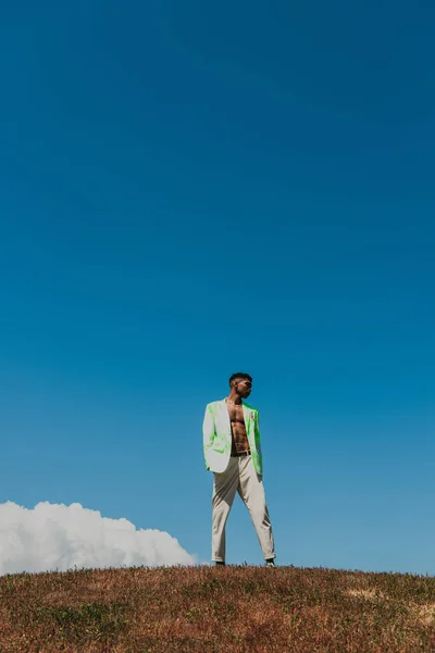 Young and fashionable african american man in grassy field under blue sky — Stock Photo