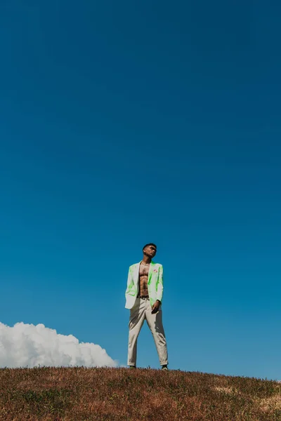 Fashionable african american man in summer clothes standing in field under blue sky — Photo de stock